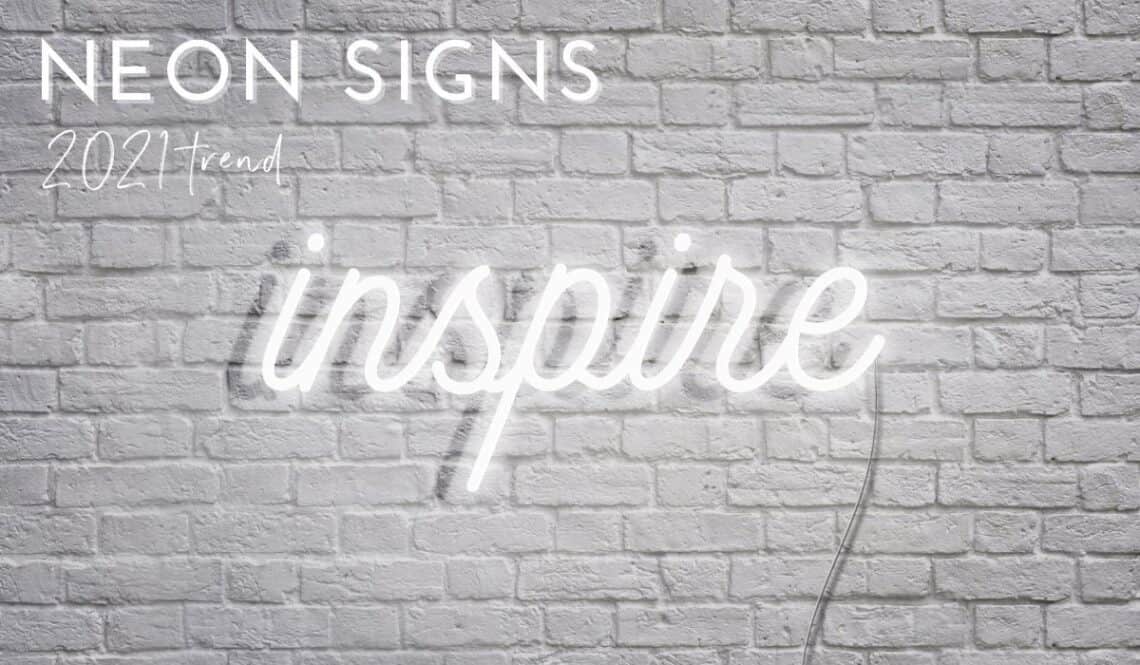 white brick wall with neon sign saying inspire