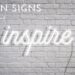 white brick wall with neon sign saying inspire