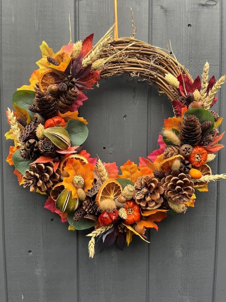 Autumn Everlasting Door Wreath. Silk autumn leaves in the gorgeous autumn colours, with dried pumpkins, orange slices a variety of natural cones and seeds, including eucalyptus and acorns, finished with a mixture of grasses.