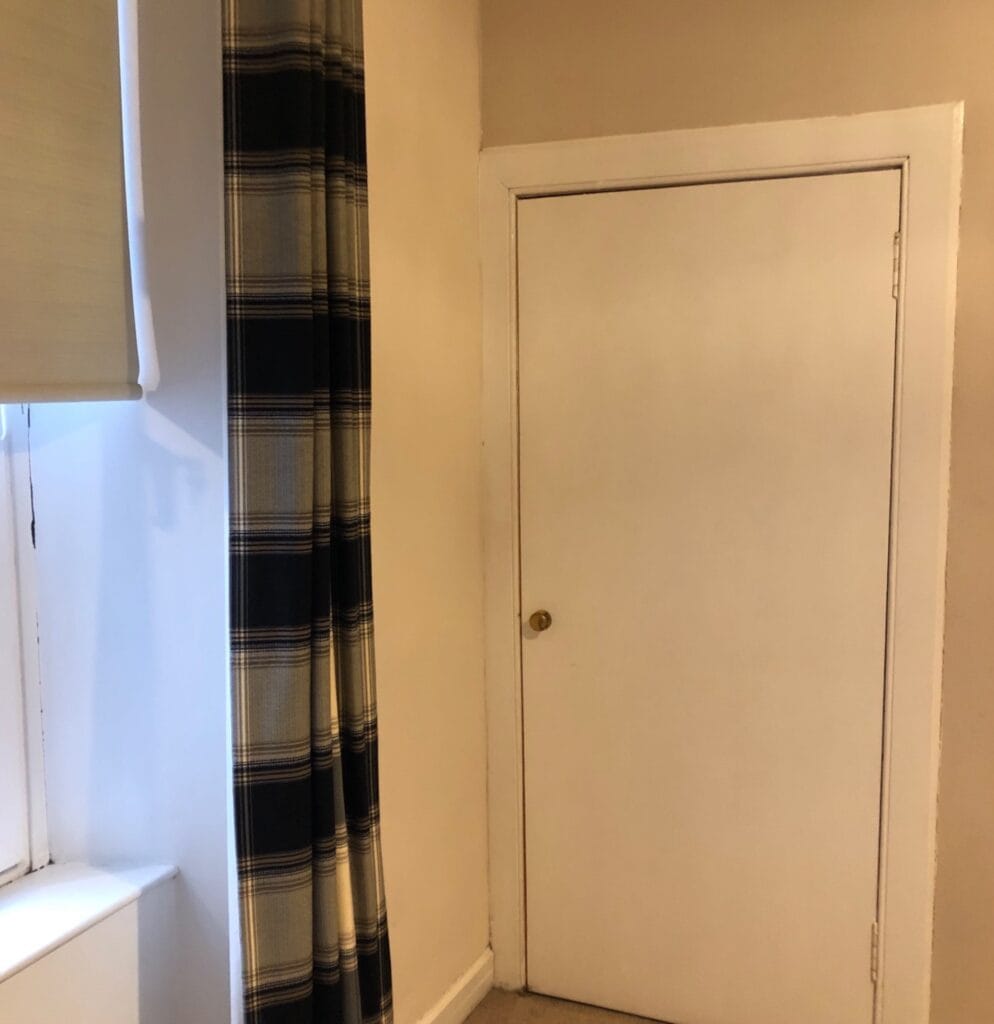 Victorian renovation - shelving area with original door in bedroom area. Features plain walls and a basic white door with a brass handle. Before bedroom renovation image.