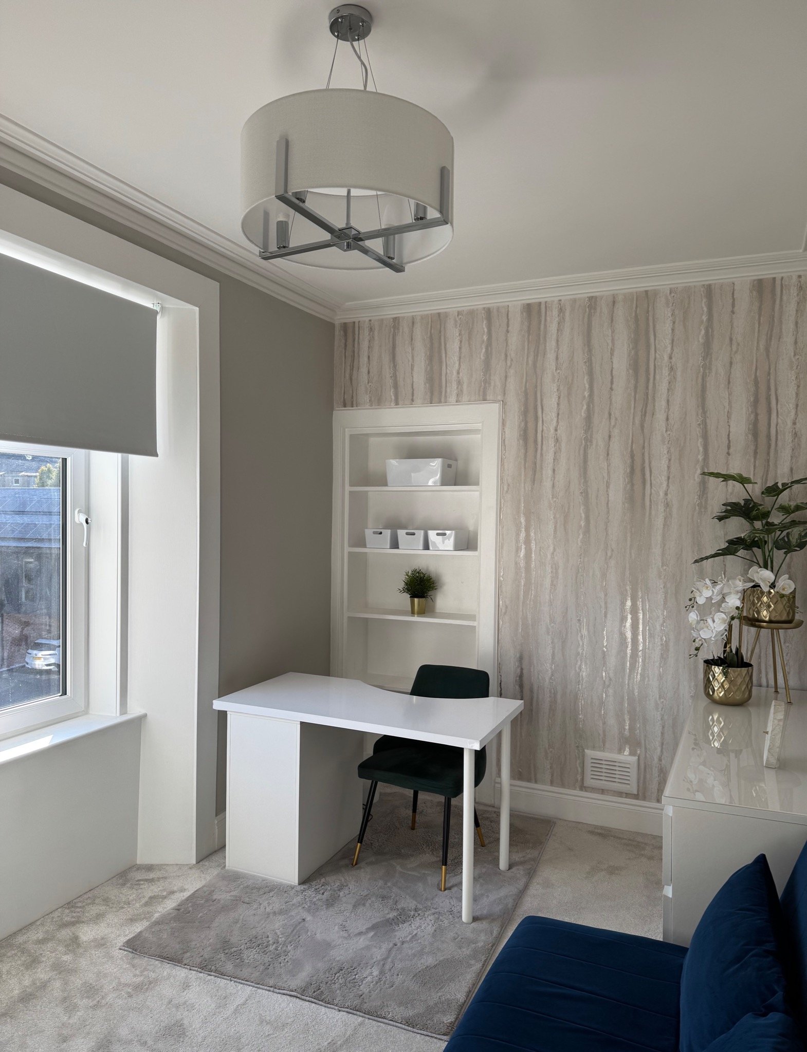 Stylish home office setup in spare room with white desk, shelves, and light metallic wallpaper. After renovation image.