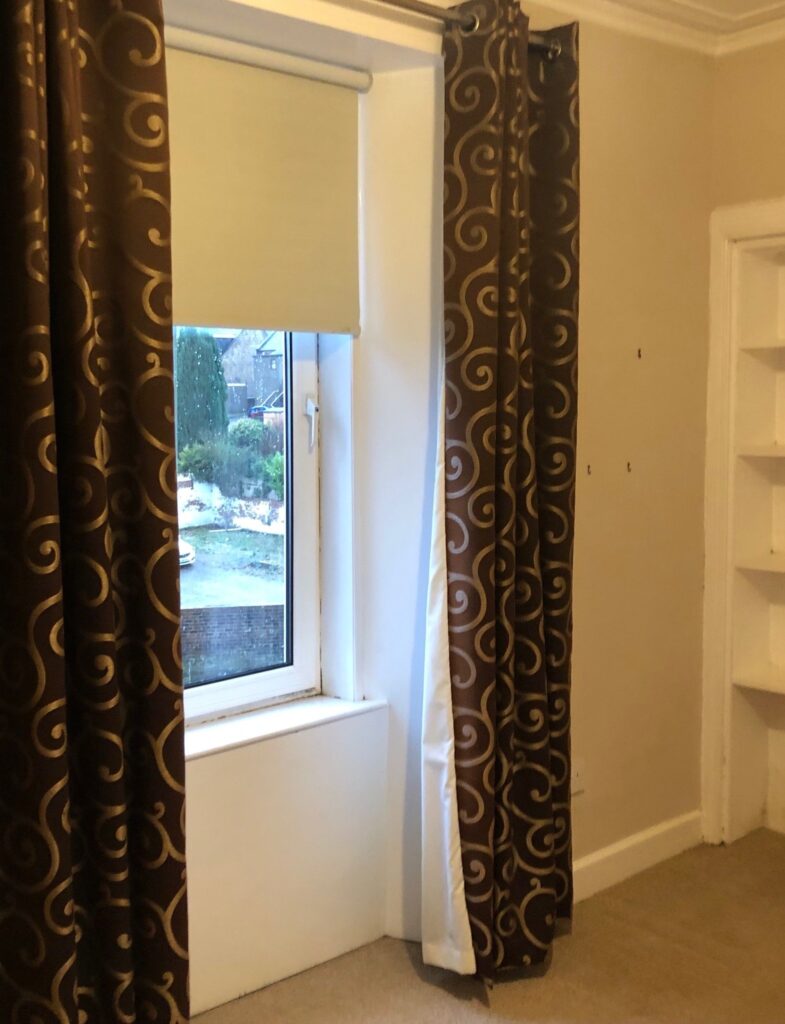 Spare room window with dark curtains and beige walls before makeover.