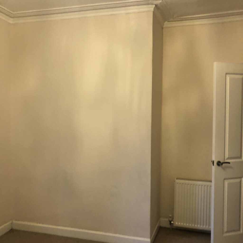 Dated bedroom before renovation - plain walls and pinky beige paint.