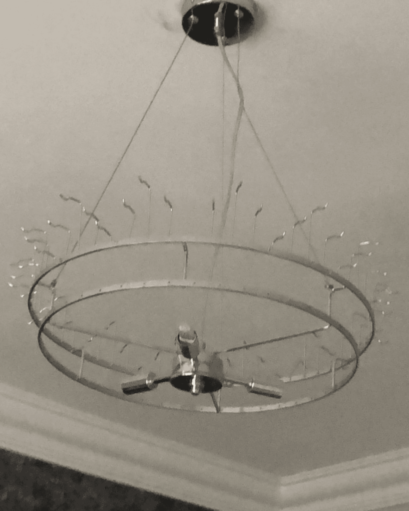 Ceiling chandelier being put together - metal frame showing, crystals still to be added.