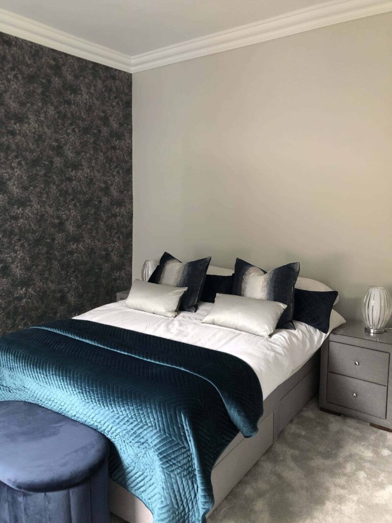 Main bedroom decor and renovation complete. Image of a navy and dark green velvet style bedroom with navy textured wallpaper and light grey paint.