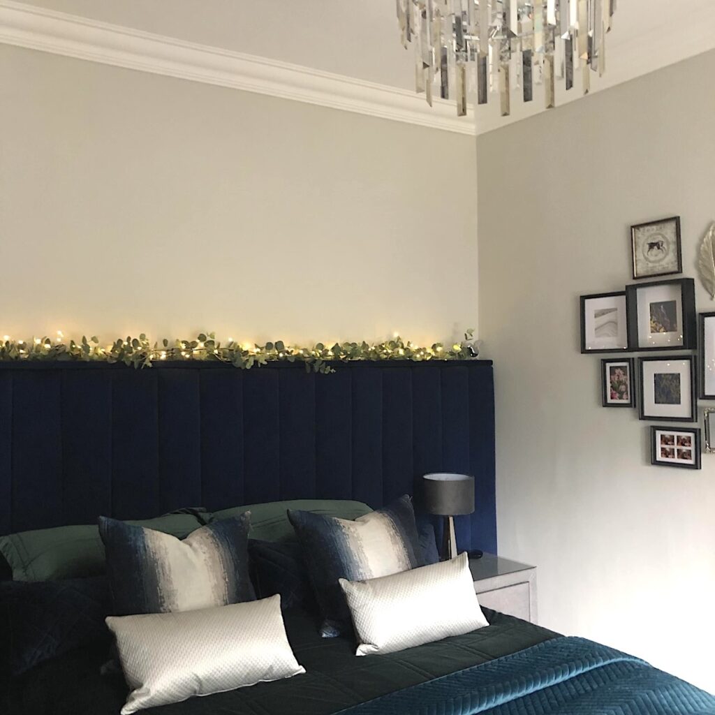After renovation main bedroom decor. Wall-to-wall headboard, navy and dark green velvet bedding and phot collage on wall.