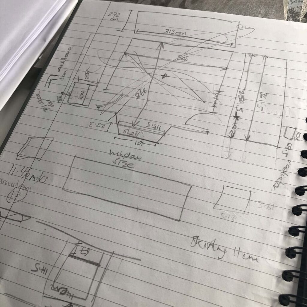 Very rough pencil sketches on a notepad of bedroom layout/design