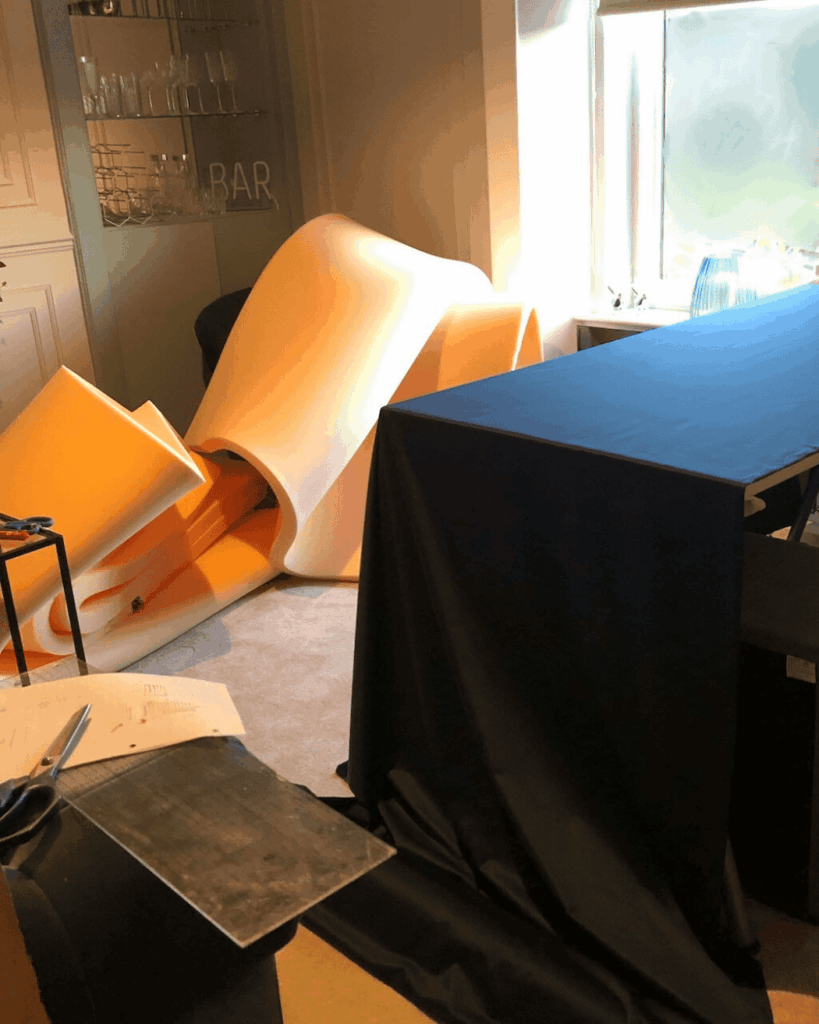 Wall-to-wall headboard getting made. Material piled up in the living room area. Navy blue fabric being used for main bedroom tall headboard.