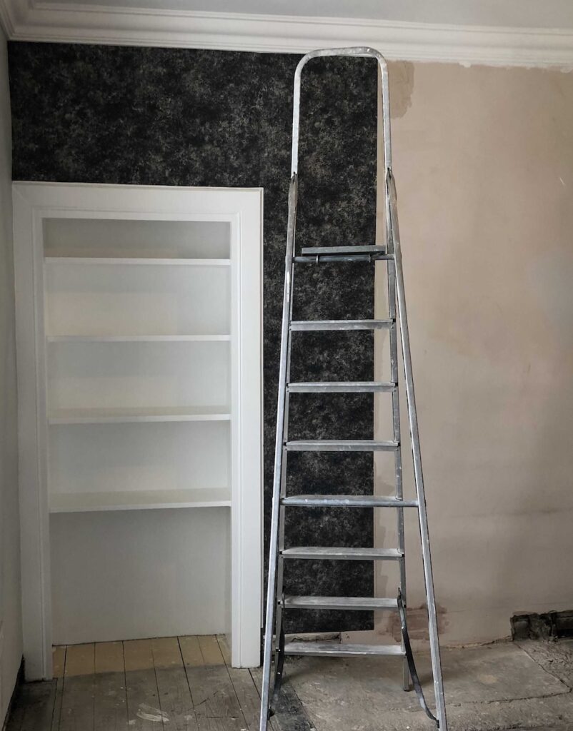 Navy blue textured wallpaper being applied - mid renovation.
