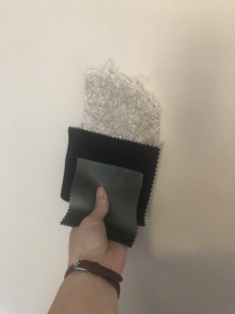 Carpet and fabric samples placed against a light grey painted wall checking they all work together.