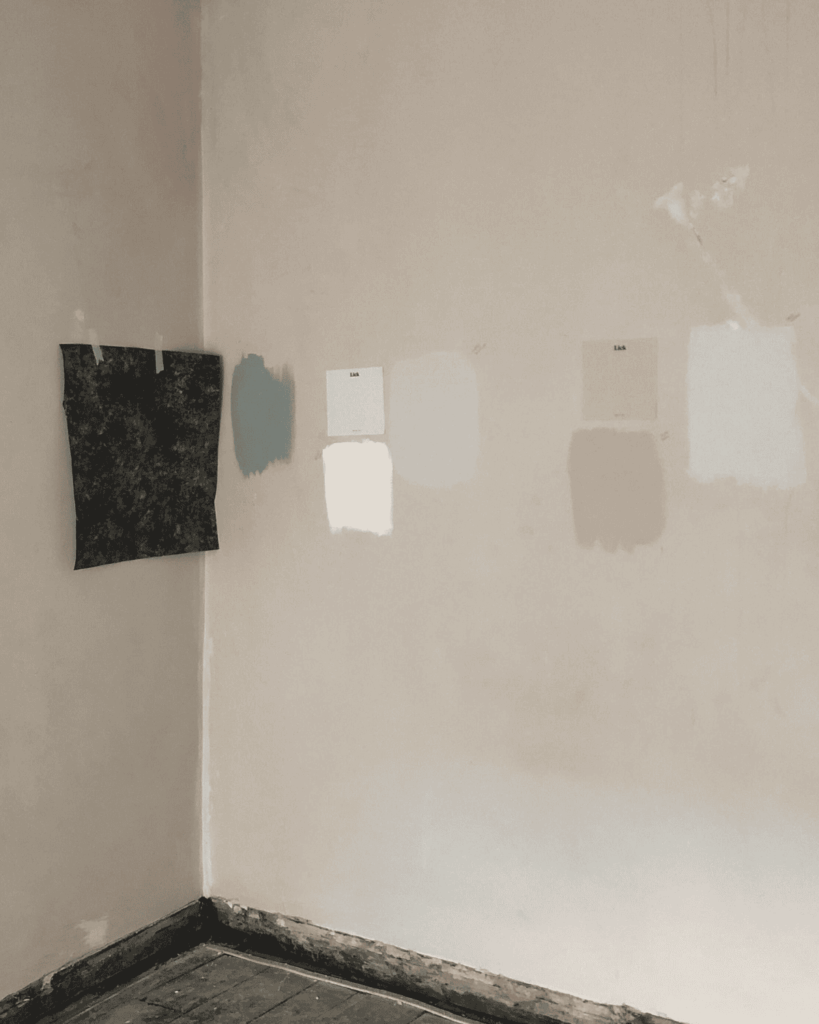 Corner of room mid renovation, wallpaper and paint swatches on walls.