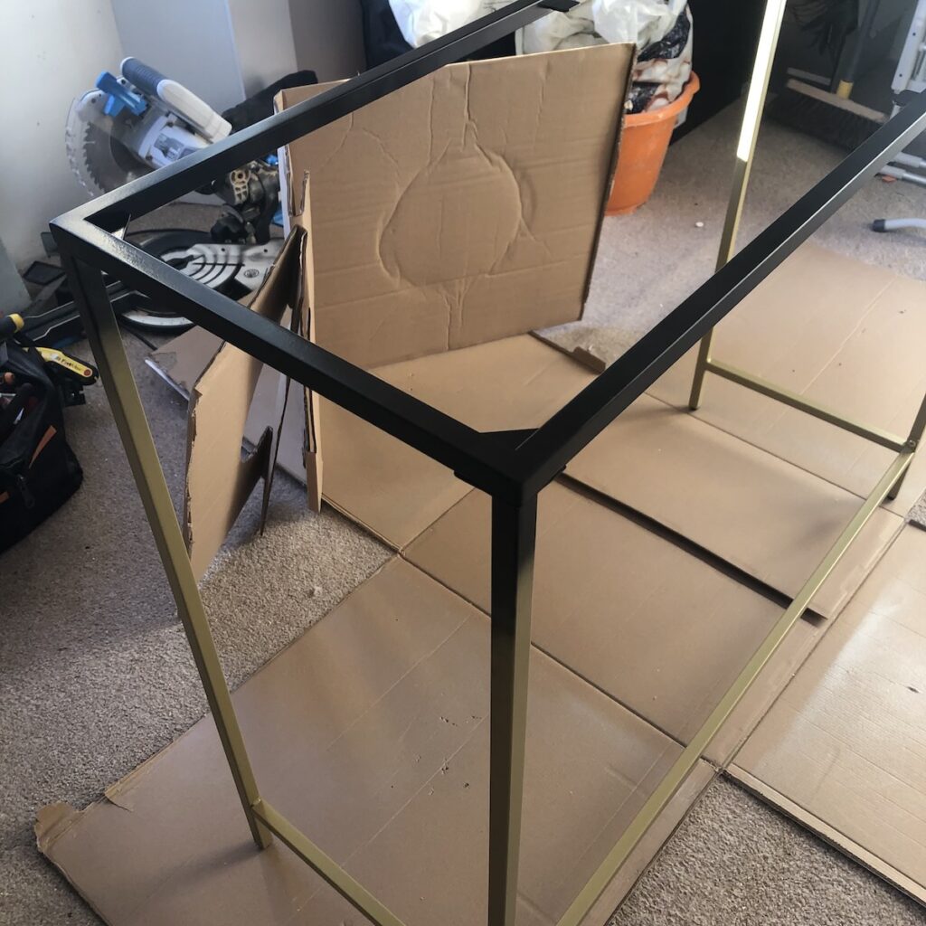 A console table being sprayed from gold to black - mid renovation
